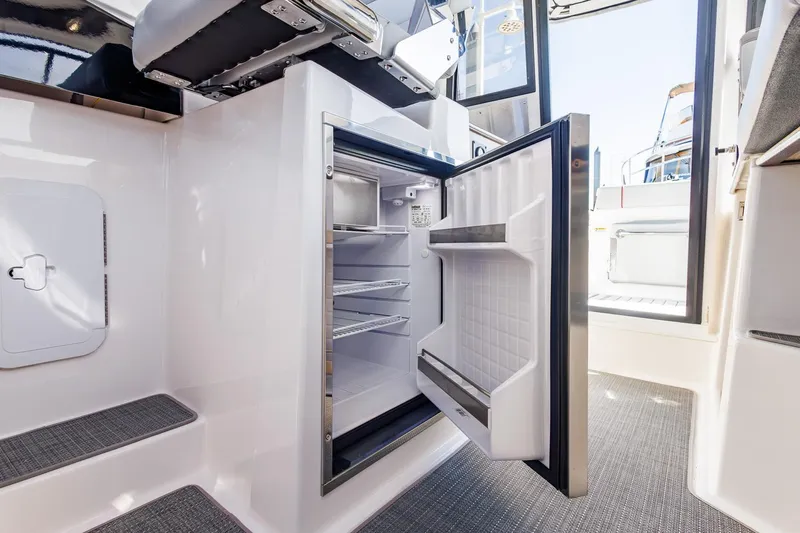  Yacht Photos Pics 2025 Solara S-250 Coupe interior with open mini fridge, modern design.