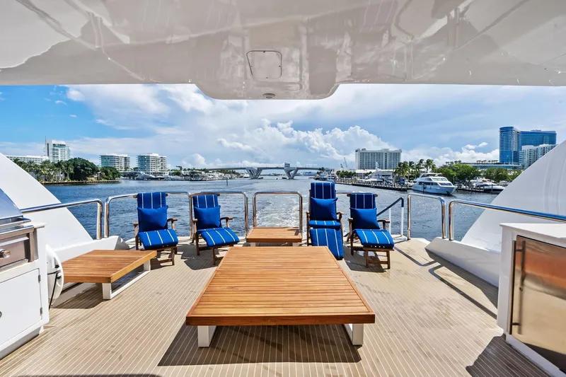 Pegasus Ix Yacht Photos Pics Luxurious Sabre 92 yacht deck with blue lounge chairs, wooden tables, and scenic waterfront view.
