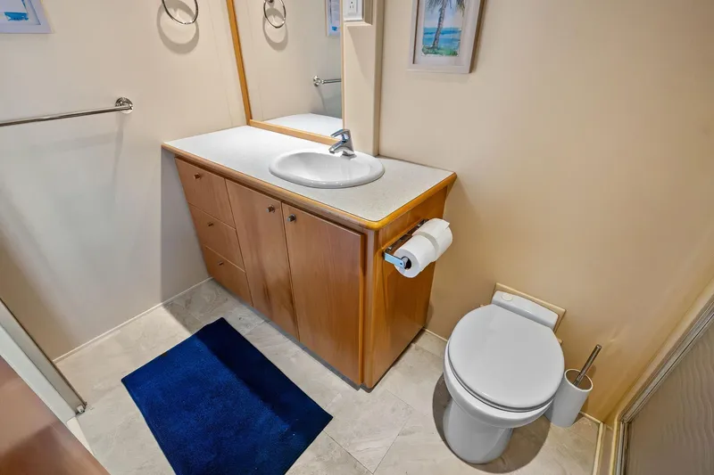 Pegasus Ix Yacht Photos Pics Compact bathroom with wooden vanity, sink, toilet, and blue rug in a 2004 Sabre 92.