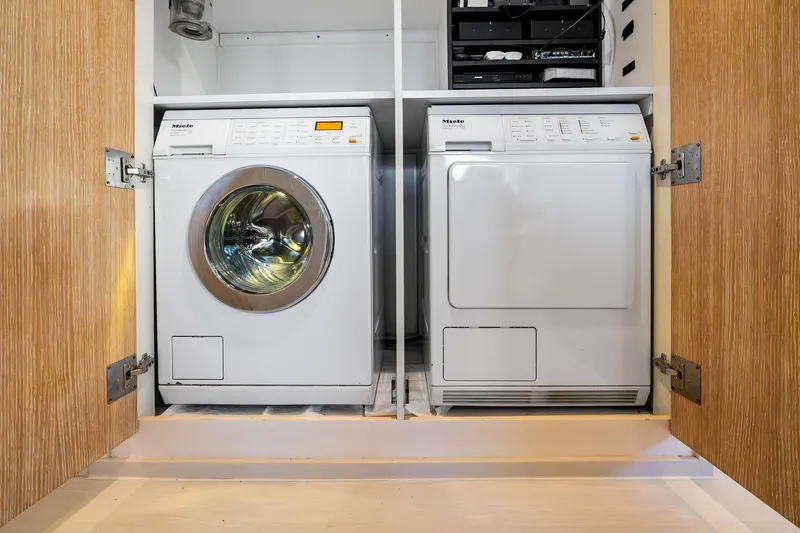 Pegasus Ix Yacht Photos Pics Laundry room with Miele washer and dryer in wooden cabinet.