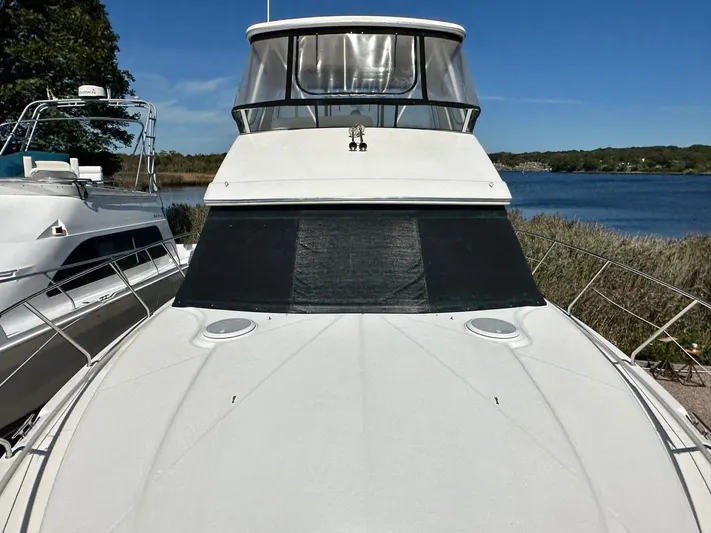 Cocktails & Dreams Yacht Photos Pics 2004 Silverton 38 Convertible yacht docked by a serene lake under clear blue skies.