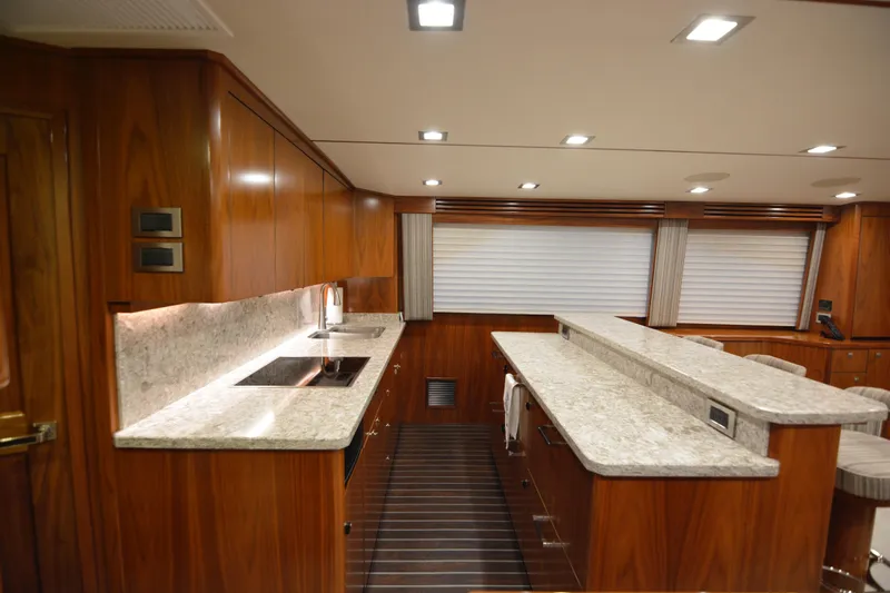 Slow Your Roll Yacht Photos Pics Luxurious kitchen interior of 2019 Viking 68 Convertible yacht with wood cabinetry and marble countertops.