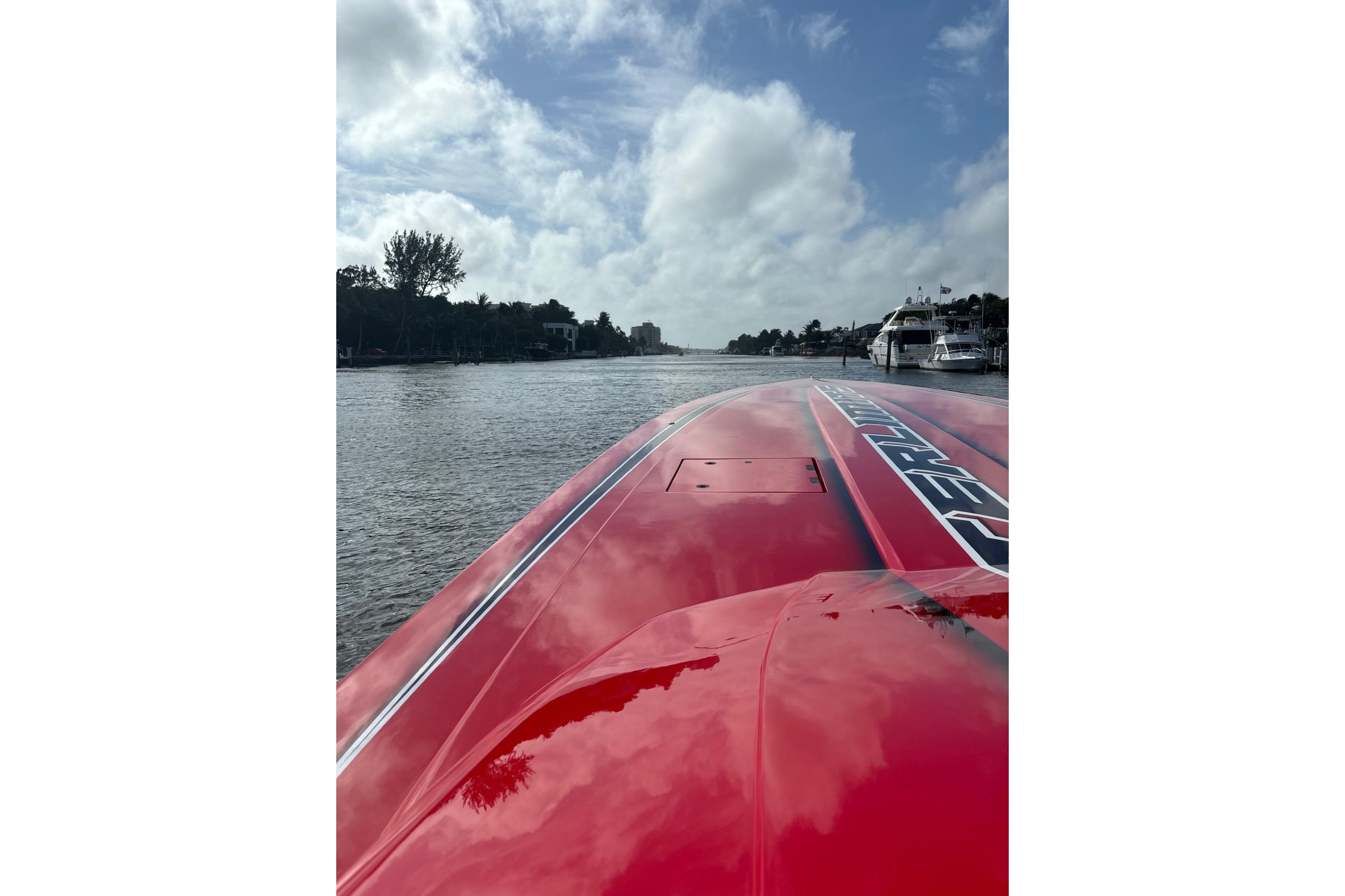 Red 2022 Outerlimits SL41 speedboat on a calm river under a partly cloudy sky.