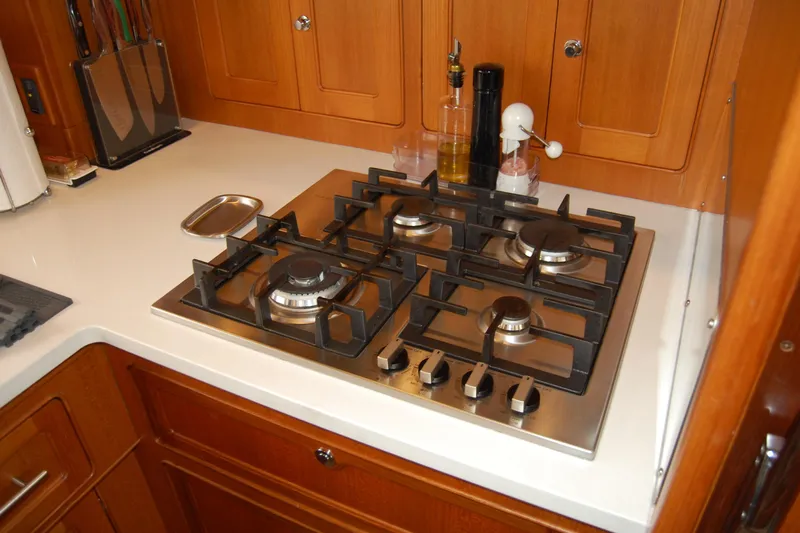 Blue Red Yacht Photos Pics Modern kitchen stove in 2006 Selene Pilothouse Ocean Trawler, featuring four burners and wooden cabinetry.