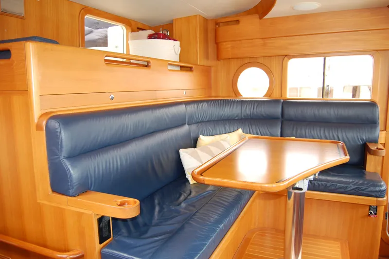 Blue Red Yacht Photos Pics Luxurious interior of 2006 Selene Pilothouse Ocean Trawler with blue leather seating and wooden table.