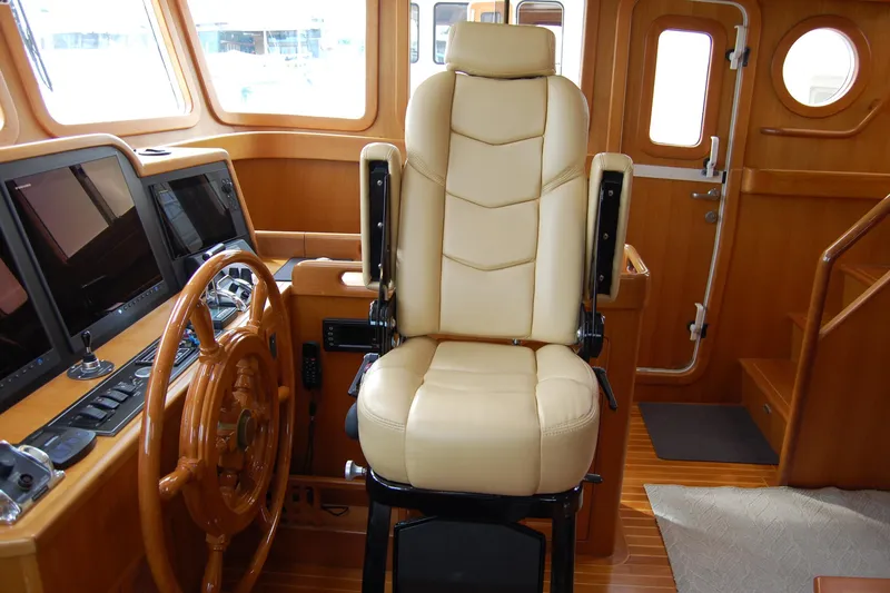 Blue Red Yacht Photos Pics Pilothouse interior of 2006 Selene Ocean Trawler with leather captain's chair and wooden steering wheel.