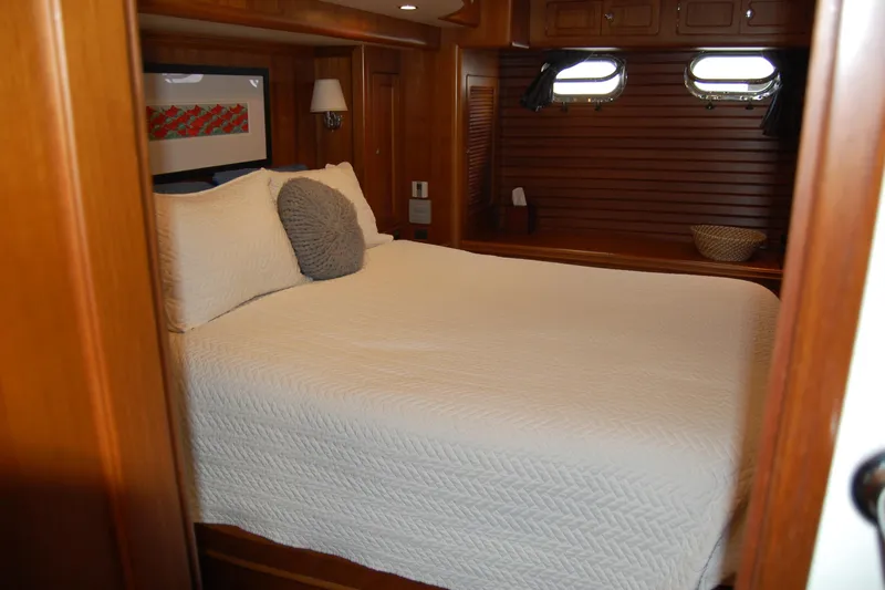 Blue Red Yacht Photos Pics Cozy bedroom in 2006 Selene Pilothouse Ocean Trawler with wooden interior and porthole windows.