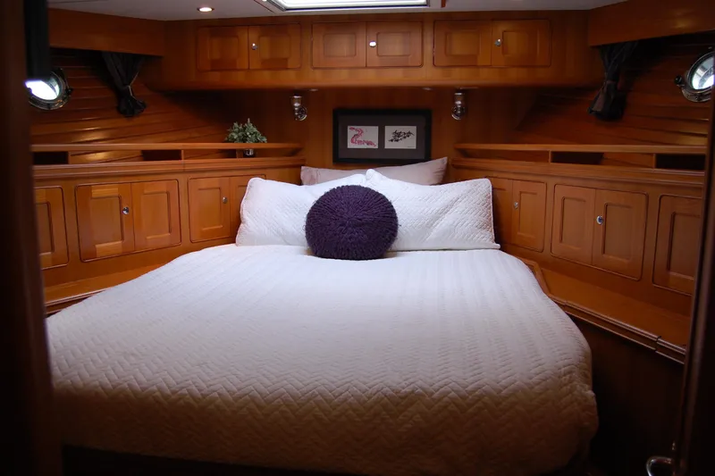 Blue Red Yacht Photos Pics Cozy cabin interior of 2006 Selene Pilothouse Ocean Trawler with wooden cabinetry and plush bedding.