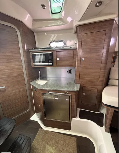  Yacht Photos Pics 2016 Boston Whaler 345 Conquest interior with kitchenette, featuring wood cabinetry and modern appliances.