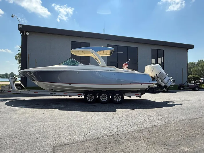 America Yacht Photos Pics 2023 Chris-Craft Launch 31 GT boat on trailer, parked outside a building under a clear sky.