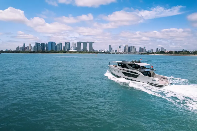  Yacht Photos Pics 2022 Bluegame BGX70 yacht cruising near a city skyline under a blue sky.
