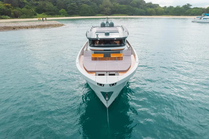  Yacht Photos Pics 2022 Bluegame BGX70 yacht on serene water near a lush shoreline.