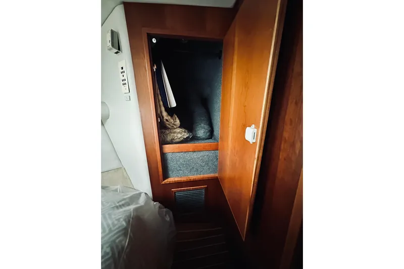 Rah Rah Yacht Photos Pics Wooden closet interior on a 2000 Riviera 40 yacht, featuring hanging clothes and storage.