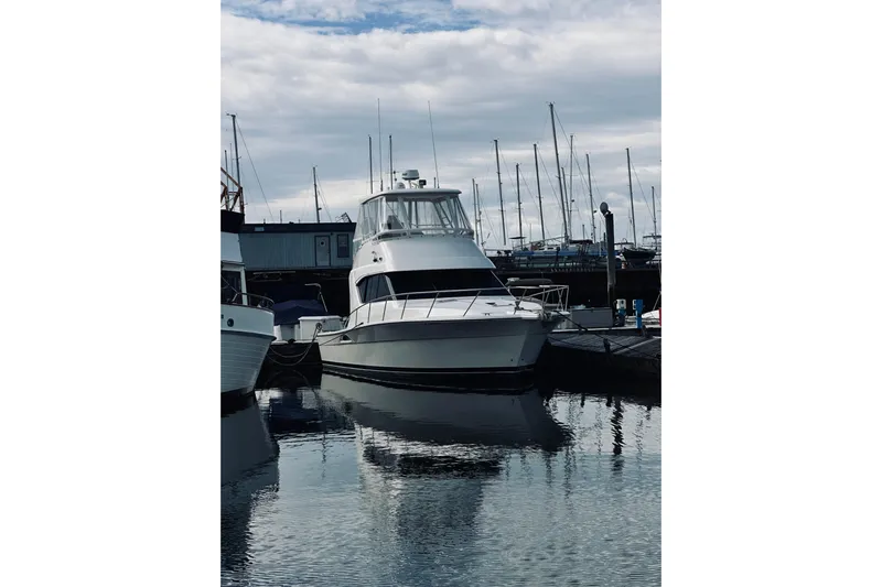 Rah Rah Yacht Photos Pics 2000 Riviera 40 yacht docked at marina, reflecting on calm water under cloudy sky.