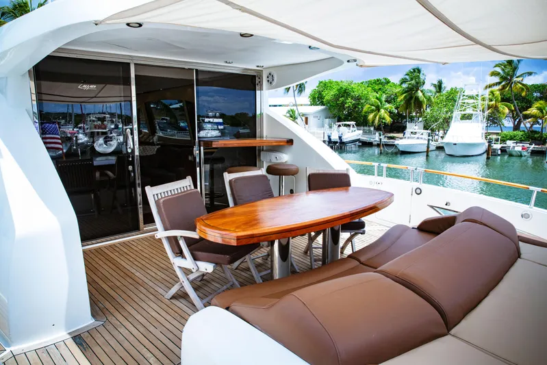 Lovin Life Yacht Photos Pics Luxurious 2008 Lazzara LSX 75 yacht deck with seating and table, docked by palm trees.