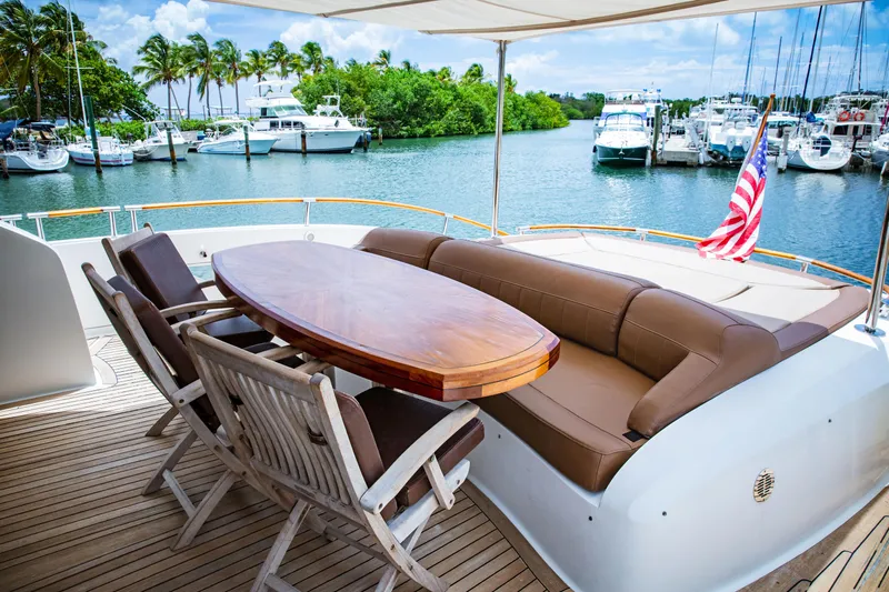 Lovin Life Yacht Photos Pics Luxurious 2008 Lazzara LSX 75 yacht deck with seating and table, docked by a scenic marina.