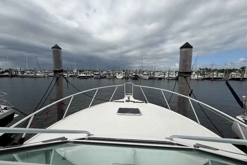 Panacea Yacht Photos Pics Bow view of 1998 Cabo 31 Express yacht docked in a marina under cloudy skies.