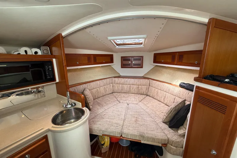 Panacea Yacht Photos Pics 1998 Cabo 31 Express cabin interior with kitchenette, seating area, and wooden cabinetry.