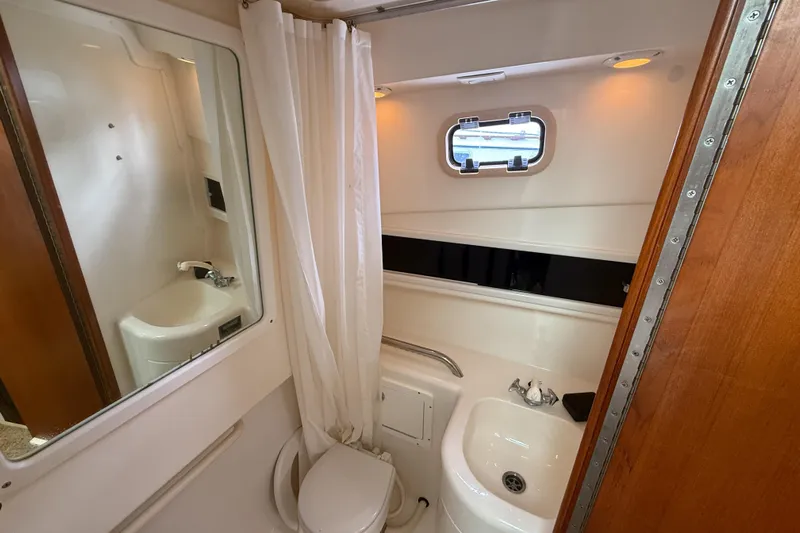Panacea Yacht Photos Pics 1998 Cabo 31 Express boat bathroom with sink, toilet, and porthole window.
