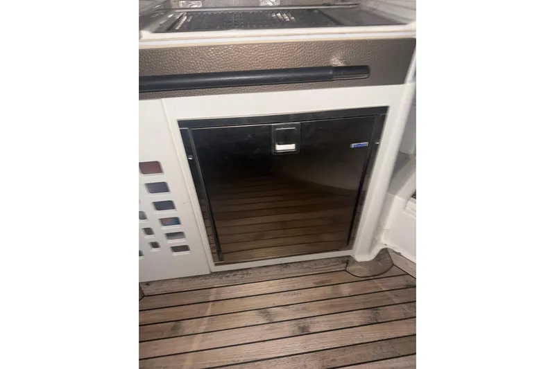  Yacht Photos Pics 2015 Sea Ray 350 SLX boat interior with a compact refrigerator and wooden flooring.