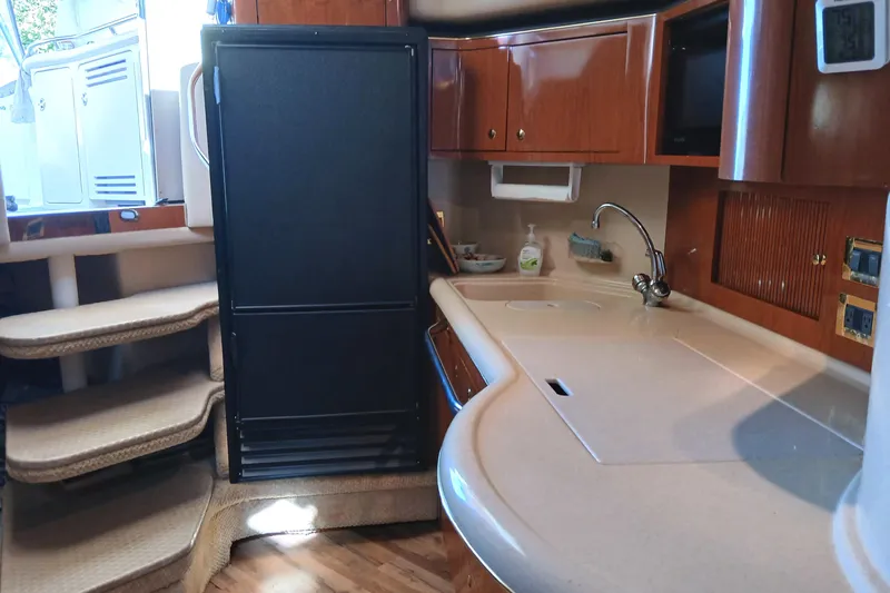Seaswing Yacht Photos Pics 2002 Sea Ray 380 Sundancer interior with kitchenette, featuring wood cabinets and a compact fridge.