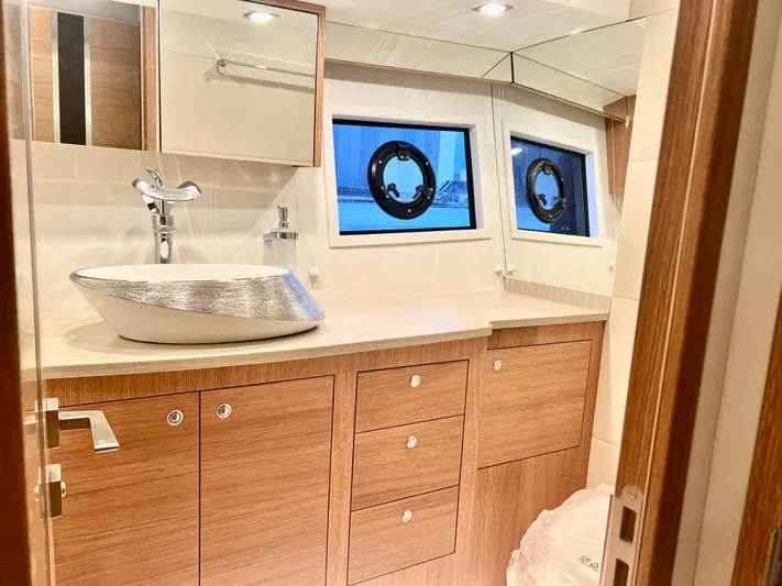 Sea At Last Yacht Photos Pics Luxurious 2025 Altima Express Coupe bathroom with modern sink, wooden cabinetry, and porthole windows.
