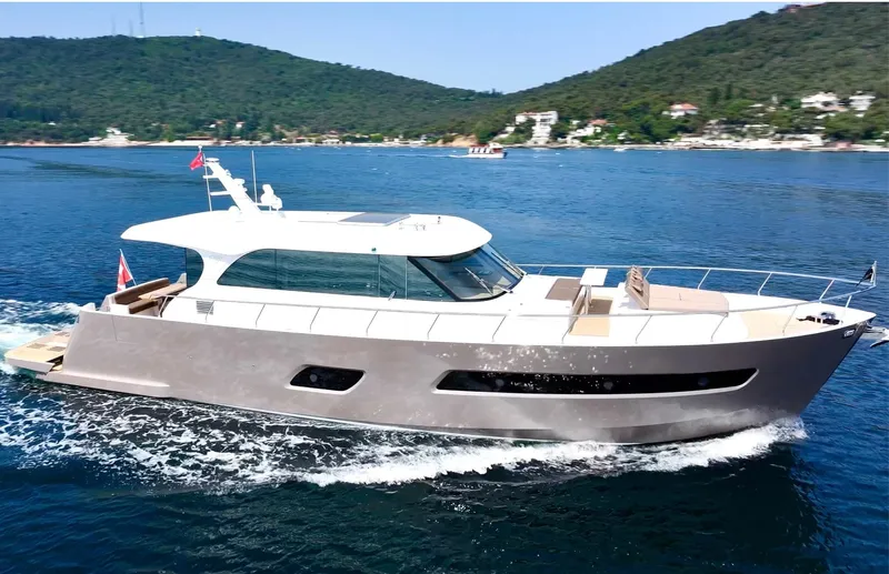 Sea At Last Yacht Photos Pics A sleek yacht cruising on blue waters near a lush, green coastline.