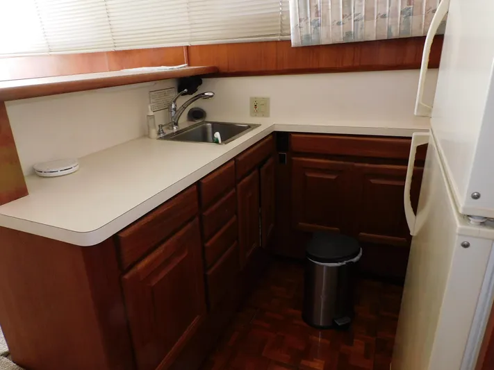 Miss Approach Yacht Photos Pics Compact kitchen in 1991 Viking 45' Convertible yacht with wooden cabinets and white countertops.