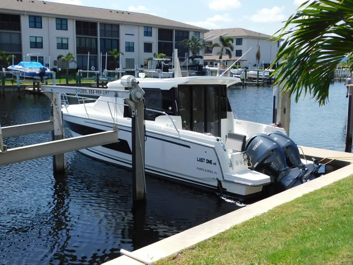  Yacht Photos Pics 2021 Jeanneau NC 1095 boat docked in a marina, surrounded by residential buildings.