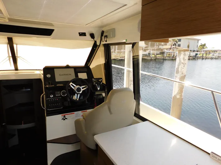  Yacht Photos Pics Interior of 2021 Jeanneau NC 1095 boat with helm, Garmin system, and waterfront view.
