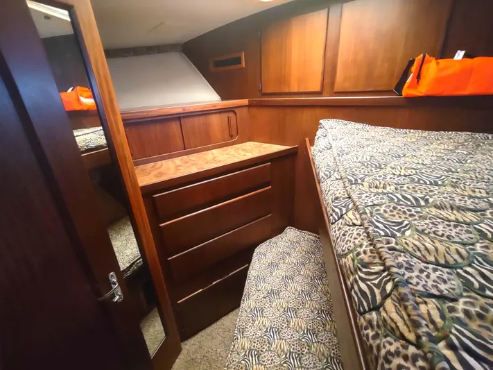  Yacht Photos Pics Cozy cabin interior of 1988 Hatteras 60 Motor Yacht with wood paneling and patterned bedding.