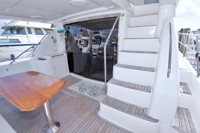Bliss Yacht Photos Pics Luxurious 2005 Neptunus 62 Flybridge yacht deck with wooden table and stairs.