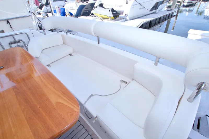 Bliss Yacht Photos Pics Luxurious seating area on a 2005 Neptunus 62 Flybridge yacht, featuring white cushions and wooden table.