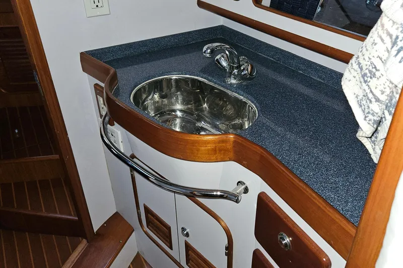 Providence Yacht Photos Pics Compact sink area in 2013 Passport 470 Center Cockpit yacht, featuring wood accents and stainless steel fixtures.