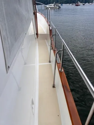 Emily Anne Yacht Photos Pics 2001 Island Gypsy Euro Sedan Trawler deck with railing, docked on calm water.