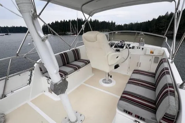 Emily Anne Yacht Photos Pics 2001 Island Gypsy Euro Sedan Trawler interior with striped seating and helm, docked by forested shoreline.