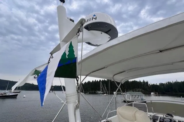 Emily Anne Yacht Photos Pics 2001 Island Gypsy Euro Sedan Trawler with flags, docked in a scenic marina.