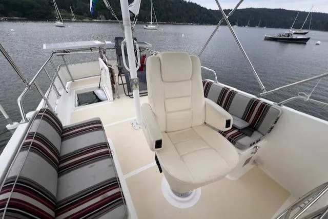 Emily Anne Yacht Photos Pics 2001 Island Gypsy Euro Sedan Trawler's deck with seating, overlooking a serene waterfront.