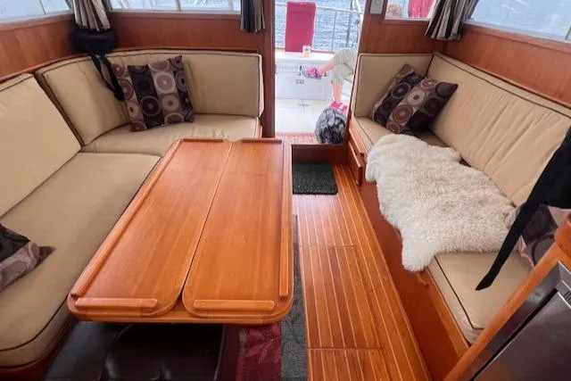 Emily Anne Yacht Photos Pics Interior of 2001 Island Gypsy Euro Sedan Trawler with cozy seating and wooden table.