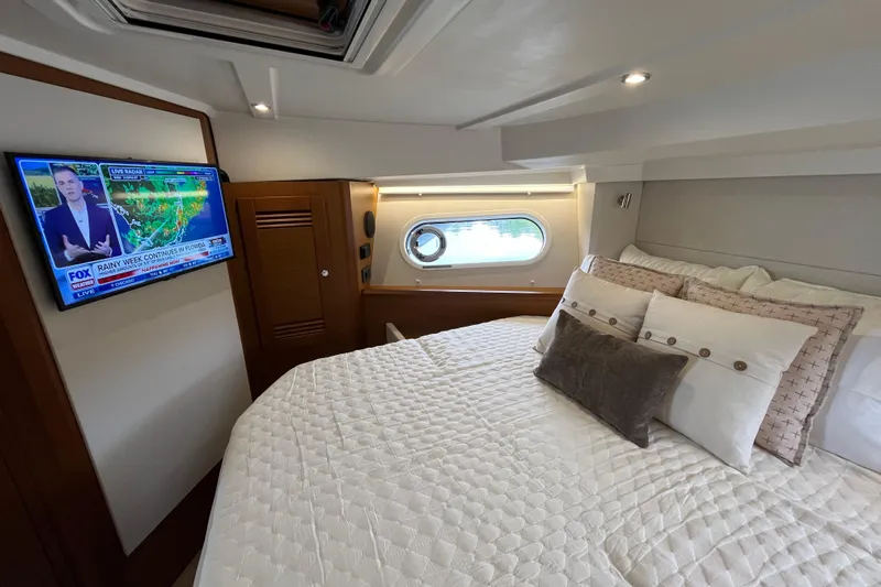  Yacht Photos Pics Luxurious bedroom in 2026 Beneteau 41 Swift Trawler Sedan with TV and porthole view.