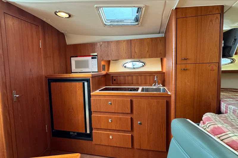  Yacht Photos Pics 2001 Tiara 31 Open yacht interior with kitchenette, featuring wood cabinetry and modern appliances.