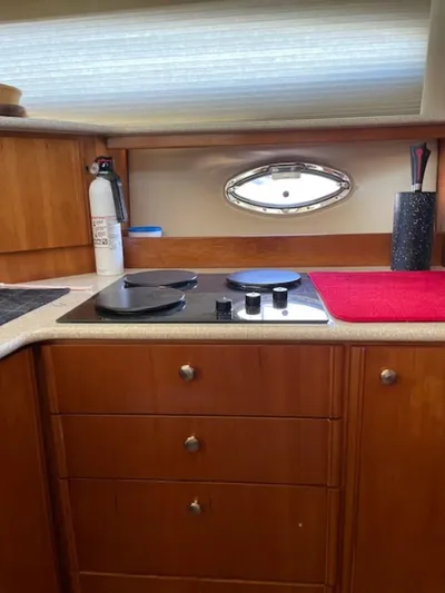 Good Times Yacht Photos Pics 2004 Meridian 459 Motoryacht kitchen with stove, wooden cabinets, and porthole window.