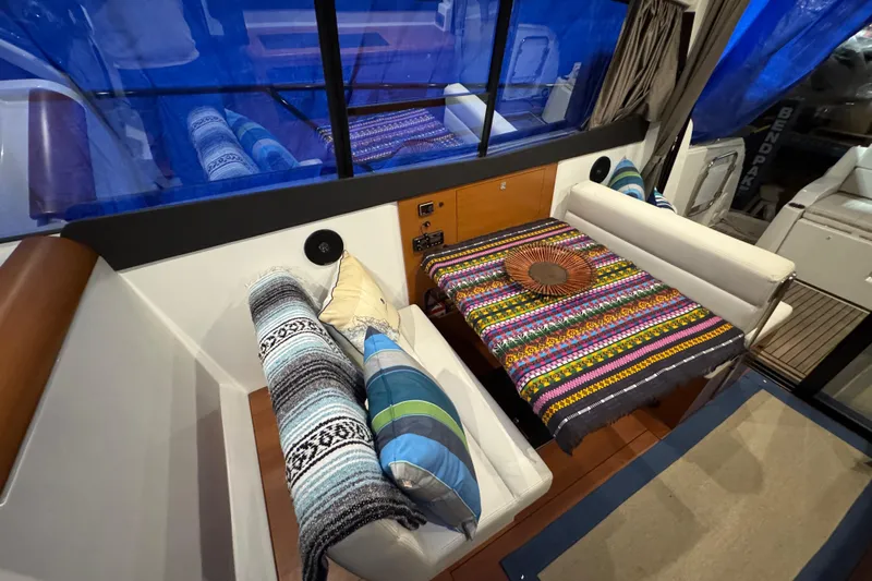  Yacht Photos Pics Interior of 2017 Jeanneau NC 9 boat with colorful cushions and tablecloth.