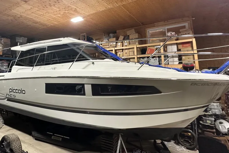  Yacht Photos Pics 2017 Jeanneau NC 9 boat in storage, surrounded by boxes and equipment.