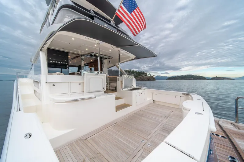  Yacht Photos Pics 2021 Riviera 64 Sports Motor Yacht with American flag, docked on serene waters.