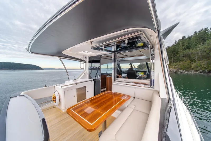  Yacht Photos Pics 2021 Riviera 64 Sports Motor Yacht with elegant outdoor seating and scenic ocean view.