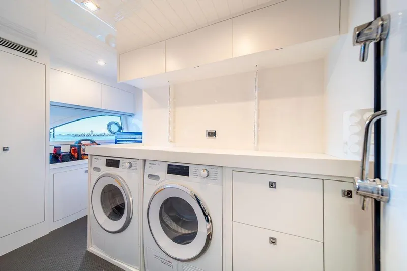  Yacht Photos Pics Laundry area inside 2021 Riviera 64 Sports Motor Yacht, featuring modern appliances and sleek design.