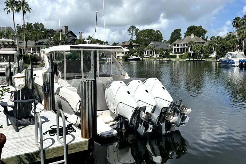  Yacht Photos Pics 2023 Tiara Yachts 38 LS docked by waterfront homes, featuring powerful outboard engines.