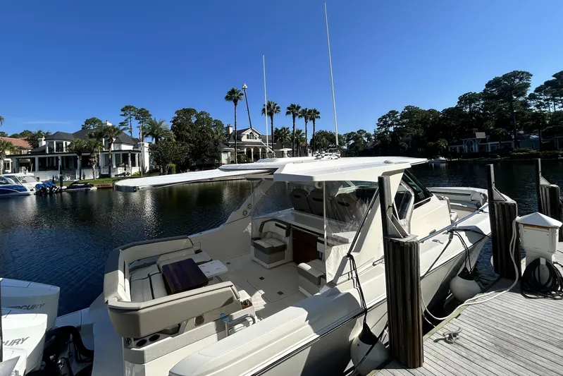  Yacht Photos Pics 2023 Tiara Yachts 38 LS docked by waterfront homes under clear blue sky.