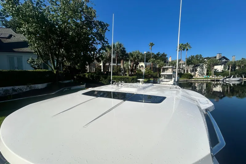  Yacht Photos Pics 2023 Tiara Yachts 38 LS on calm water, surrounded by lush greenery and luxury homes.